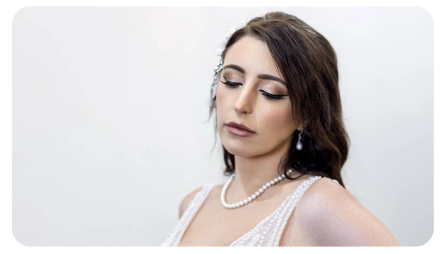 A woman in an elegant sleeveless dress adorned with pearls, showcasing a graceful pose against a neutral background.